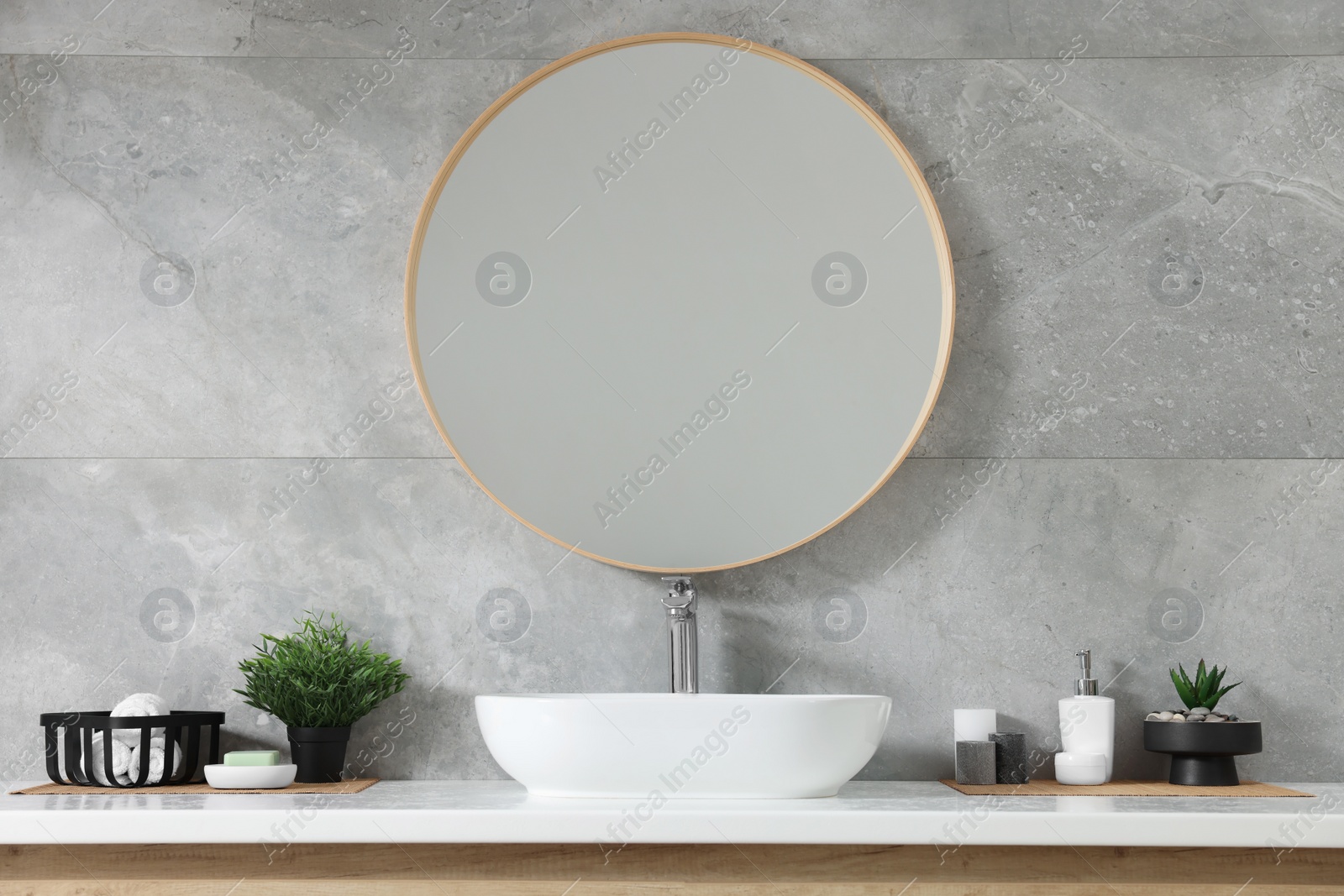 Photo of Potted artificial plants, rolled towels and soap near sink on bathroom vanity