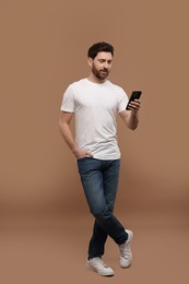 Photo of Handsome man with smartphone on light brown background