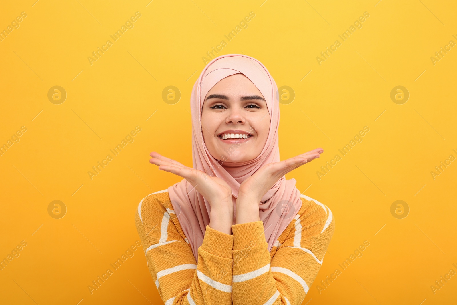 Photo of Portrait of Muslim woman in hijab on orange background