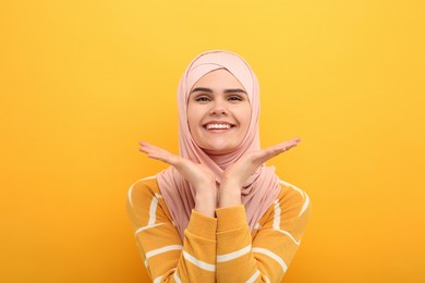 Portrait of Muslim woman in hijab on orange background