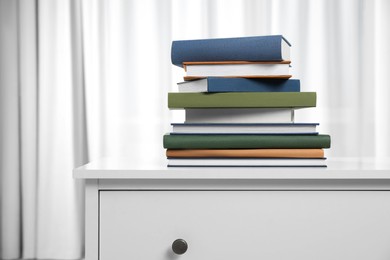 Photo of Hardcover books on white chest of drawers indoors