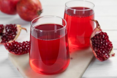Photo of Tasty pomegranate juice in glasses and fresh fruits on white wooden table, closeup