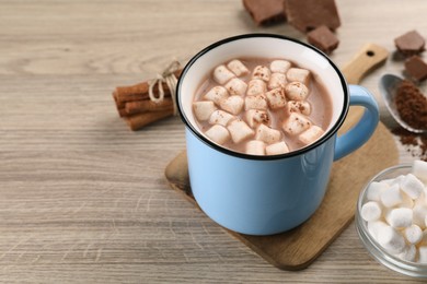 Photo of Cup of aromatic hot chocolate with marshmallows, and cocoa powder on wooden table, closeup. Space for text