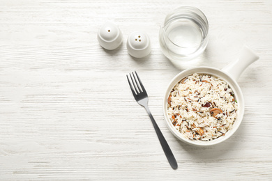 Photo of Delicious rice pilaf with mushrooms on white wooden table, flat lay. Space for text
