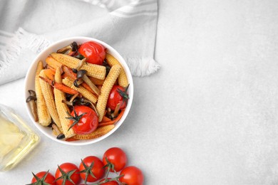 Tasty roasted baby corn with tomatoes and mushrooms on white table, flat lay. Space for text