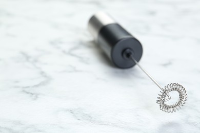 Photo of Black milk frother wand on white marble table, closeup. Space for text