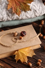 Book with autumn leaf as bookmark, acorns and warm sweaters on wooden table