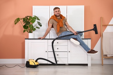 Photo of Young man with vacuum cleaner at home