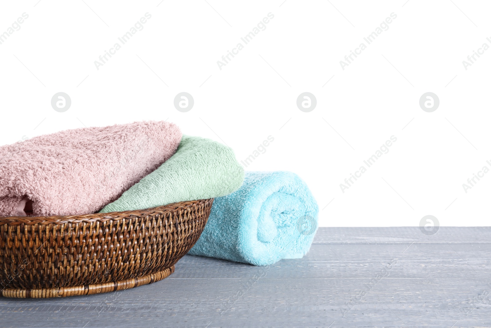 Photo of Fresh towels on grey wooden table against white background. Space for text