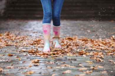 Woman wearing rubber boots after rain, focus on legs. Autumn walk