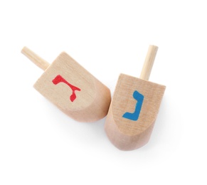 Photo of Wooden Hanukkah traditional dreidels with letters Gimel and Nun on white background, top view