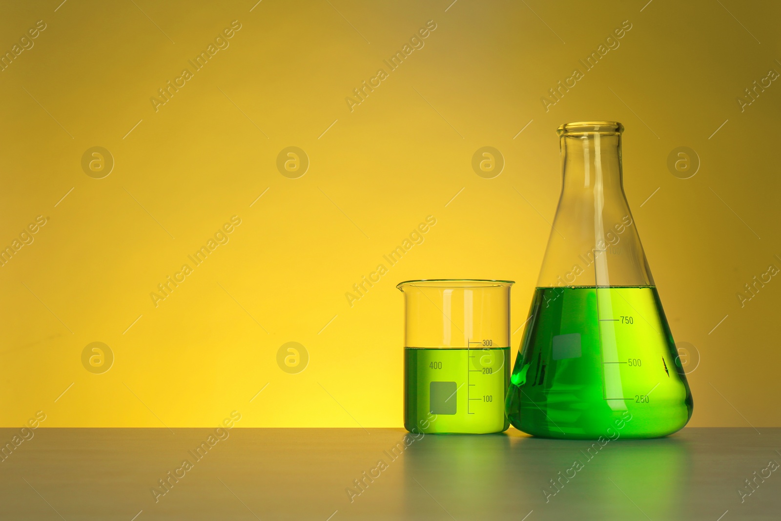 Photo of Chemistry laboratory glassware with samples on table against color background