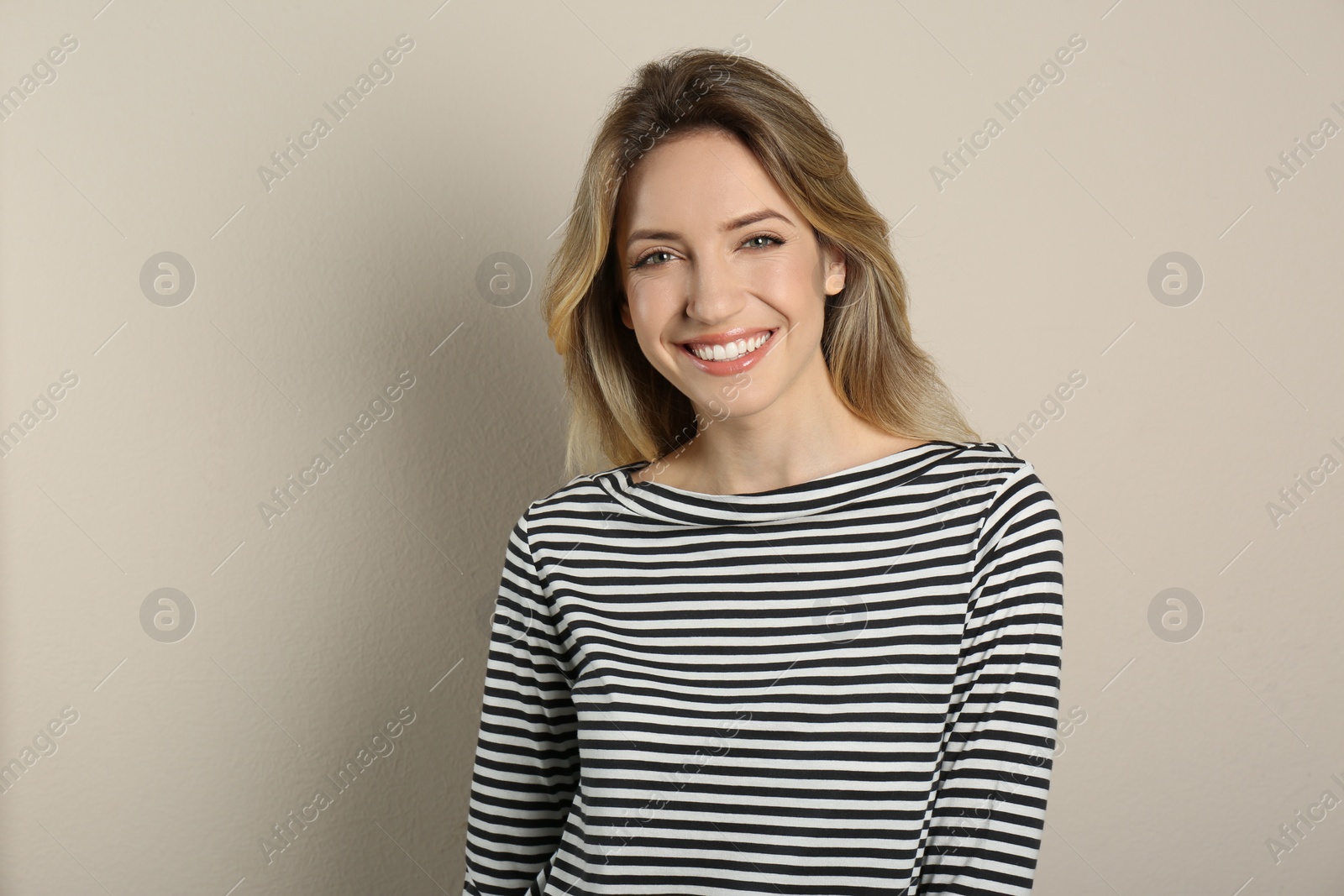 Photo of Portrait of happy young woman with beautiful blonde hair and charming smile on beige background