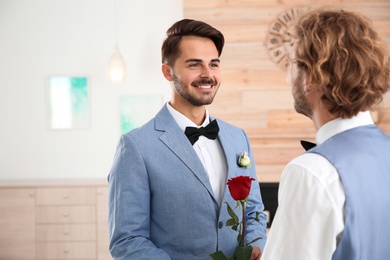 Photo of Happy newlywed gay couple with flower at home