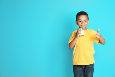 Photo of Adorable African-American boy with glass of milk on color background