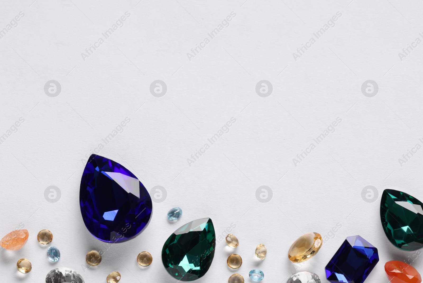 Photo of Different beautiful gemstones for jewelry on white background, top view. Space for text