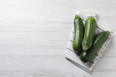 Photo of Raw ripe zucchinis on white wooden table, flat lay. Space for text