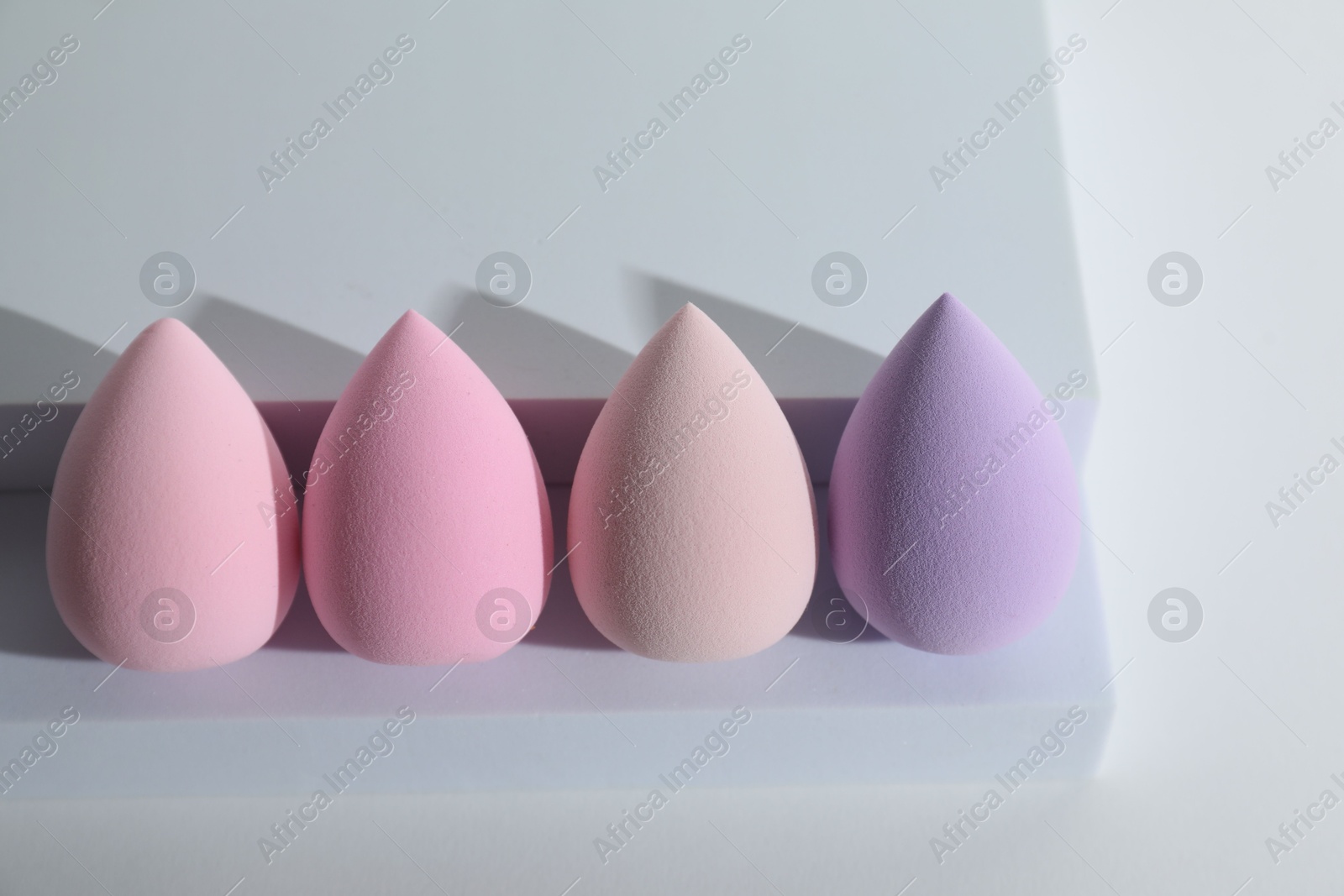 Photo of Stylish presentation of makeup sponges on white background, above view