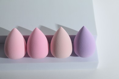 Stylish presentation of makeup sponges on white background, above view