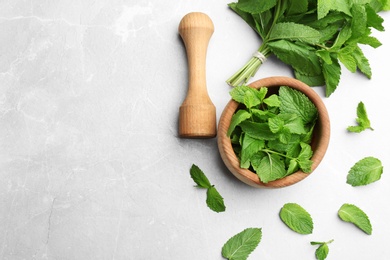 Photo of Fresh mint with mortar and pestle on grey marble background, flat lay. Space for text