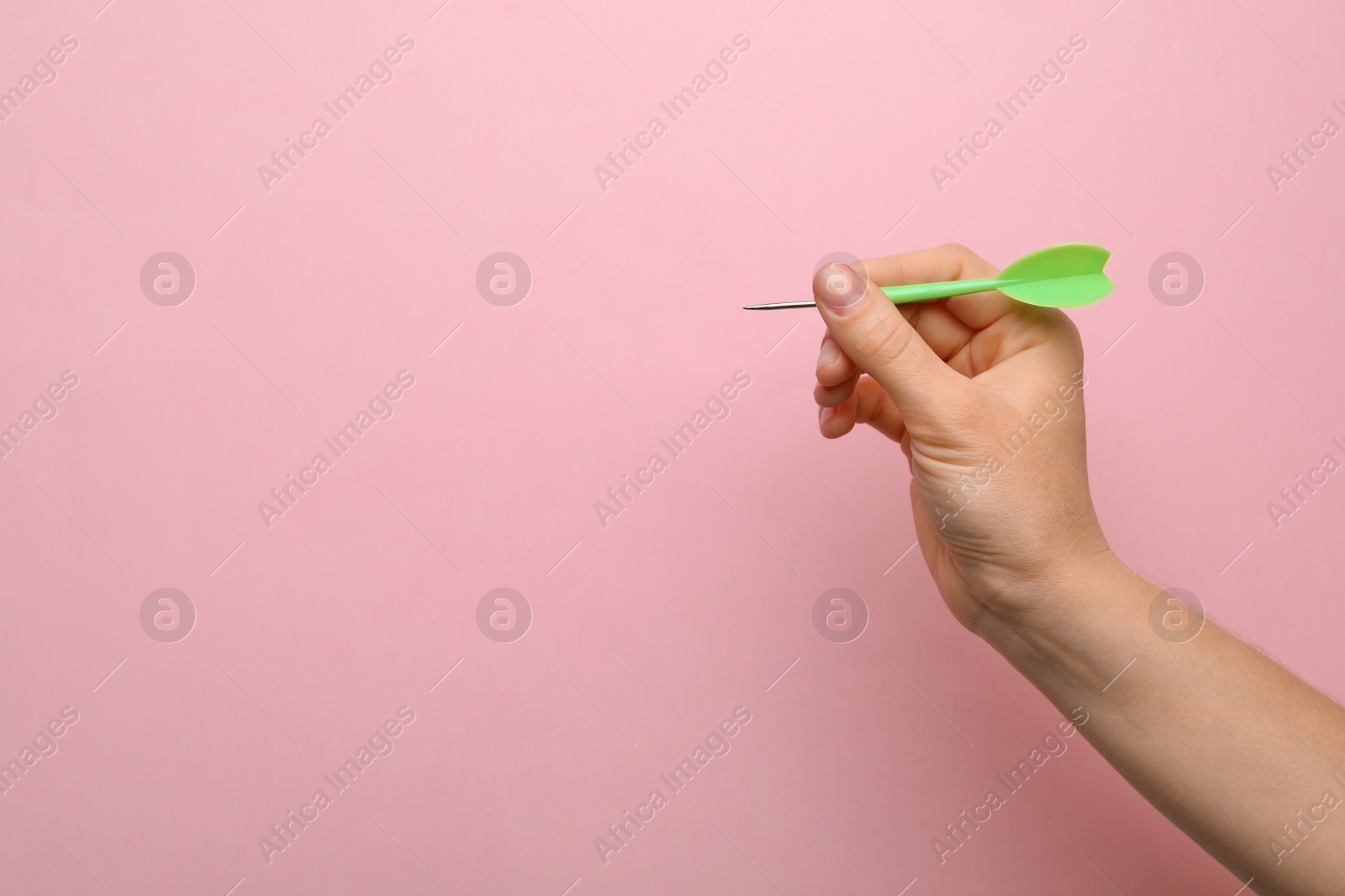 Photo of Woman holding green dart arrow on pink background, closeup with space for text