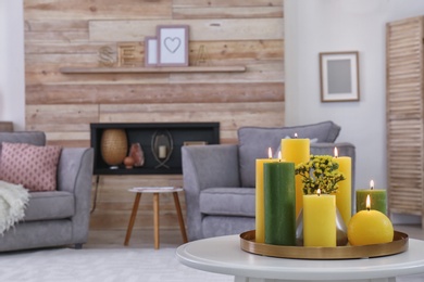 Tray with burning candles on table in living room