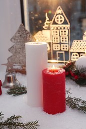 Photo of Beautiful burning candles with Christmas decor near window