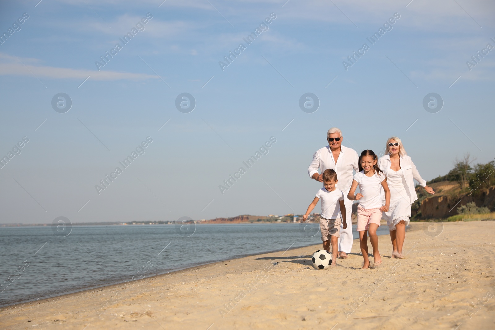 Photo of Cute little children with grandparents spending time together on sea beach