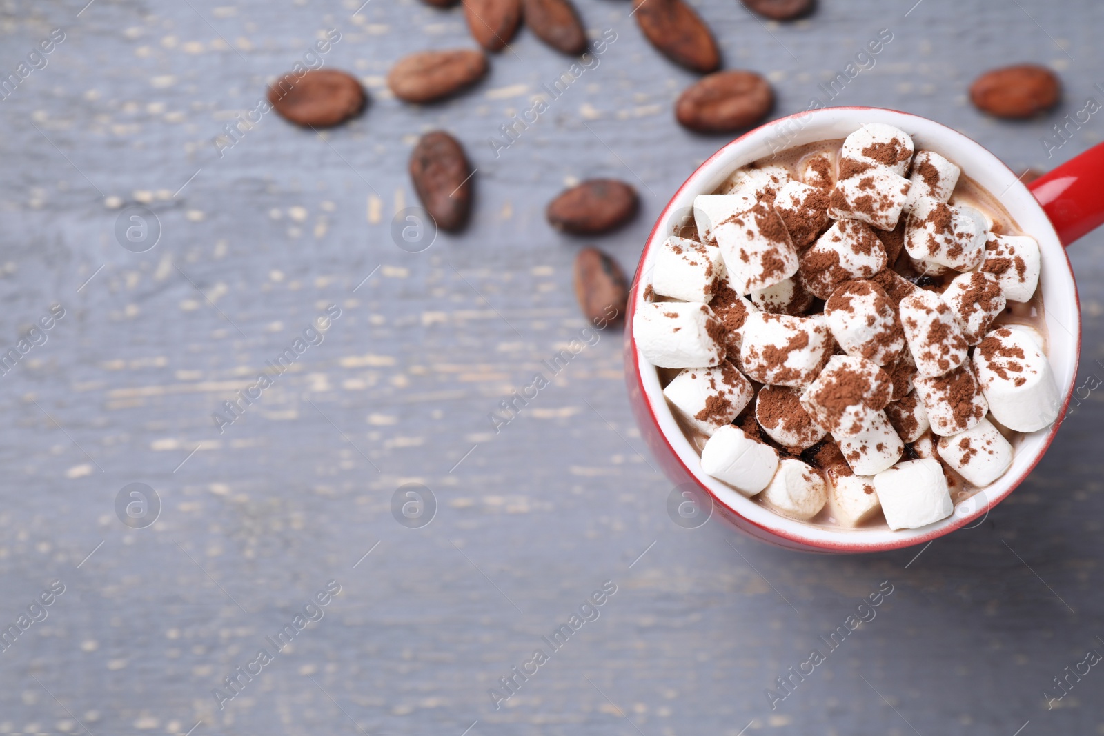 Photo of Cup of tasty cocoa with marshmallows and beans on grey wooden table, top view. Space for text