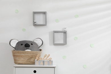 Wooden cubes and wicker basket on chest of drawers indoors. Children's room interior