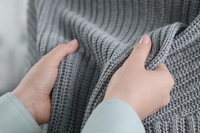 Photo of Woman touching clothes made of soft knitted fabric, closeup