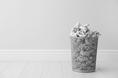 Photo of Metal bin and crumpled paper against light wall, space for text