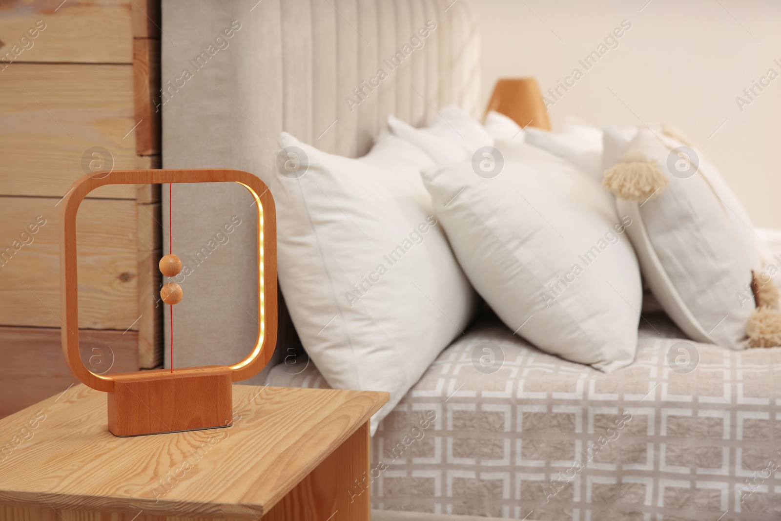 Photo of Modern lamp on nightstand near bed in hotel