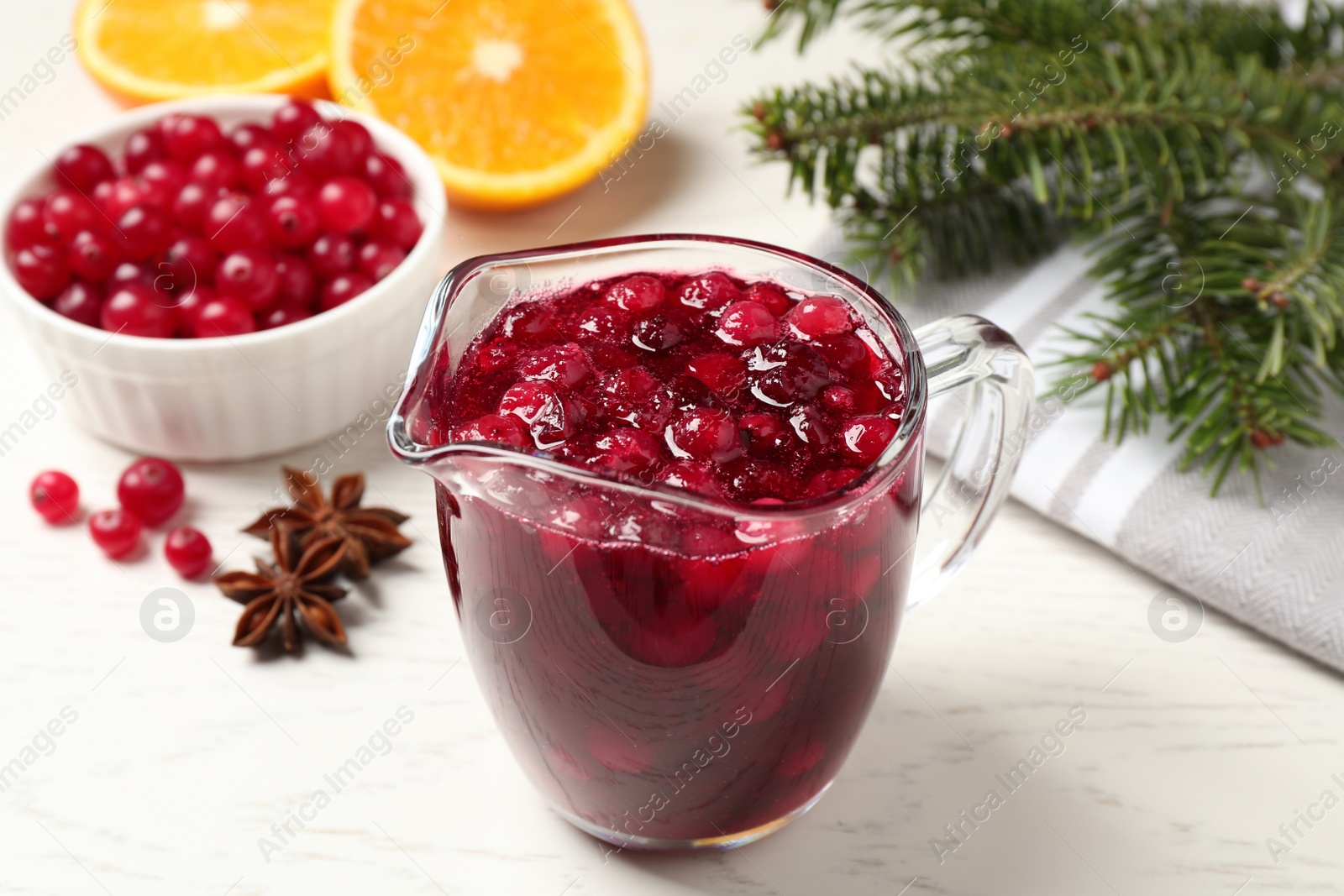 Photo of Fresh cranberry sauce in pitcher on white table