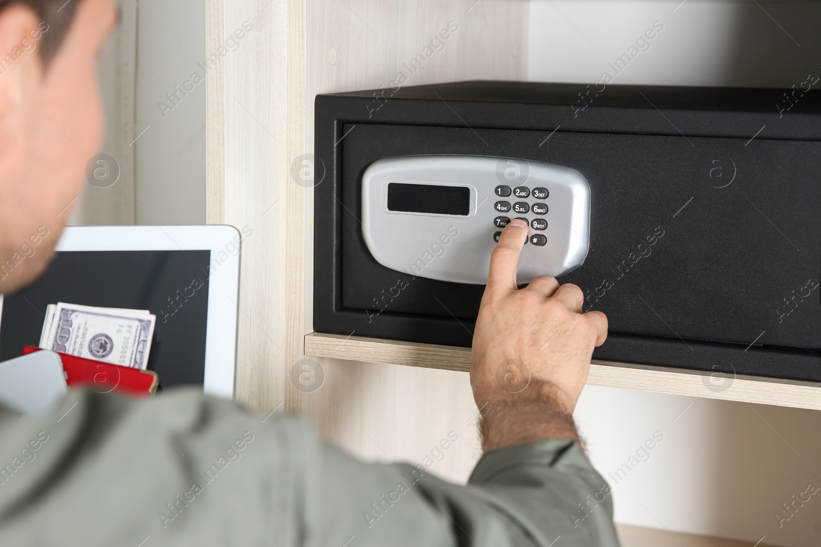 Photo of Man opening black steel safe with electronic lock at hotel, closeup