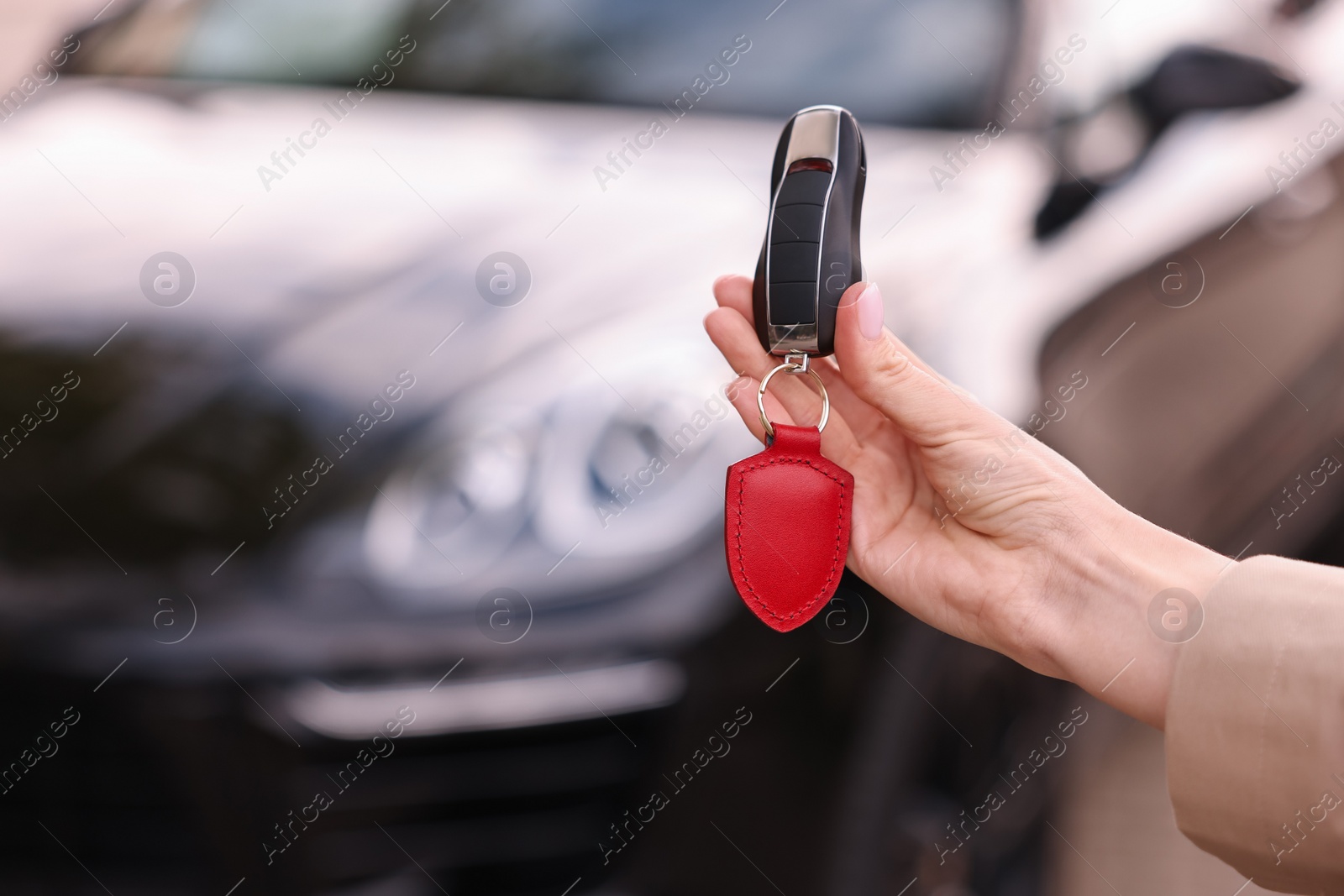 Photo of Woman holding car flip key near her vehicle outdoors, closeup