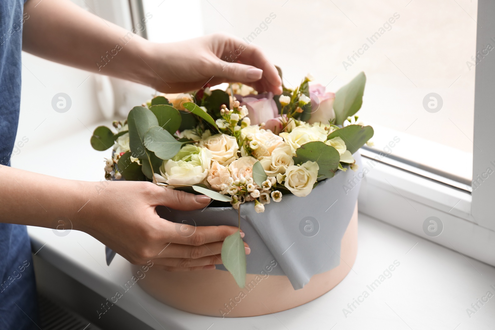 Photo of Female florist holding box with flowers indoors