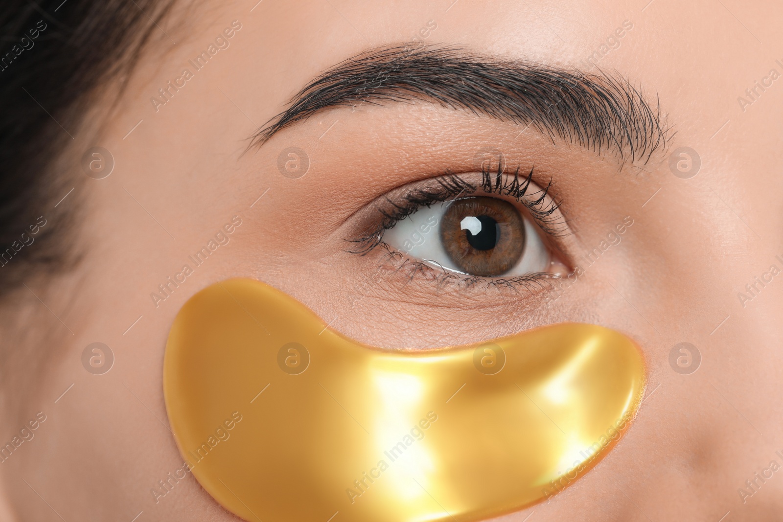 Photo of Young woman with golden under eye patch, closeup