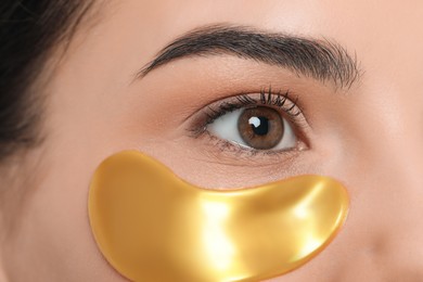 Photo of Young woman with golden under eye patch, closeup