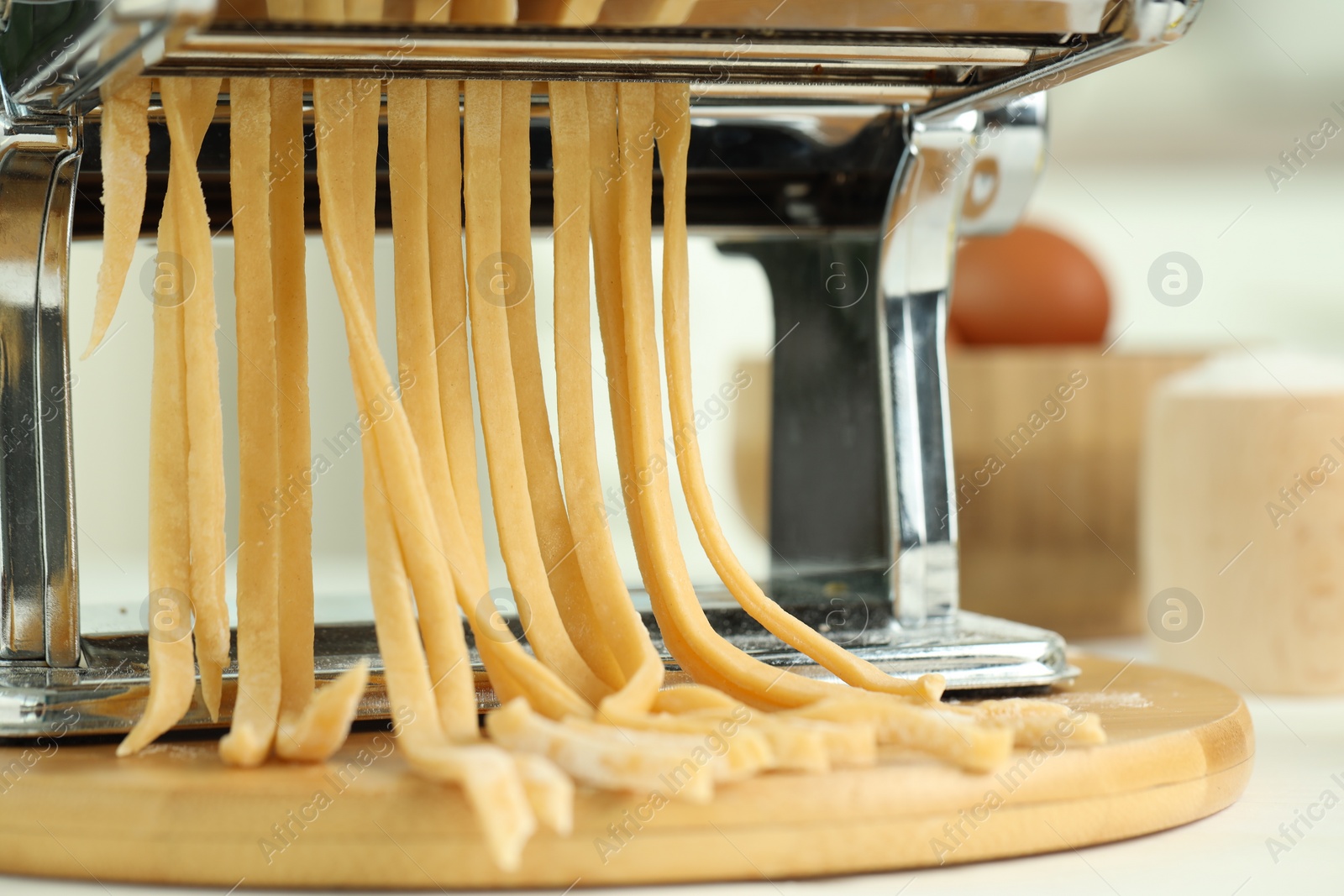 Photo of Pasta maker with raw dough on wooden table, closeup