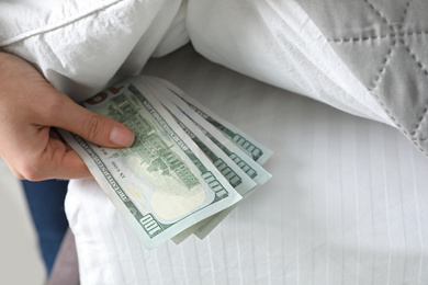 Photo of Woman hiding dollar banknotes under blanket in bedroom, closeup. Money savings