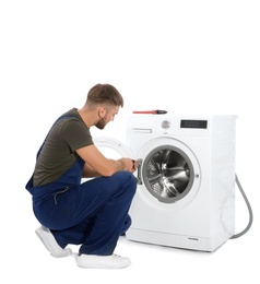 Plumber fixing washing machine on white background