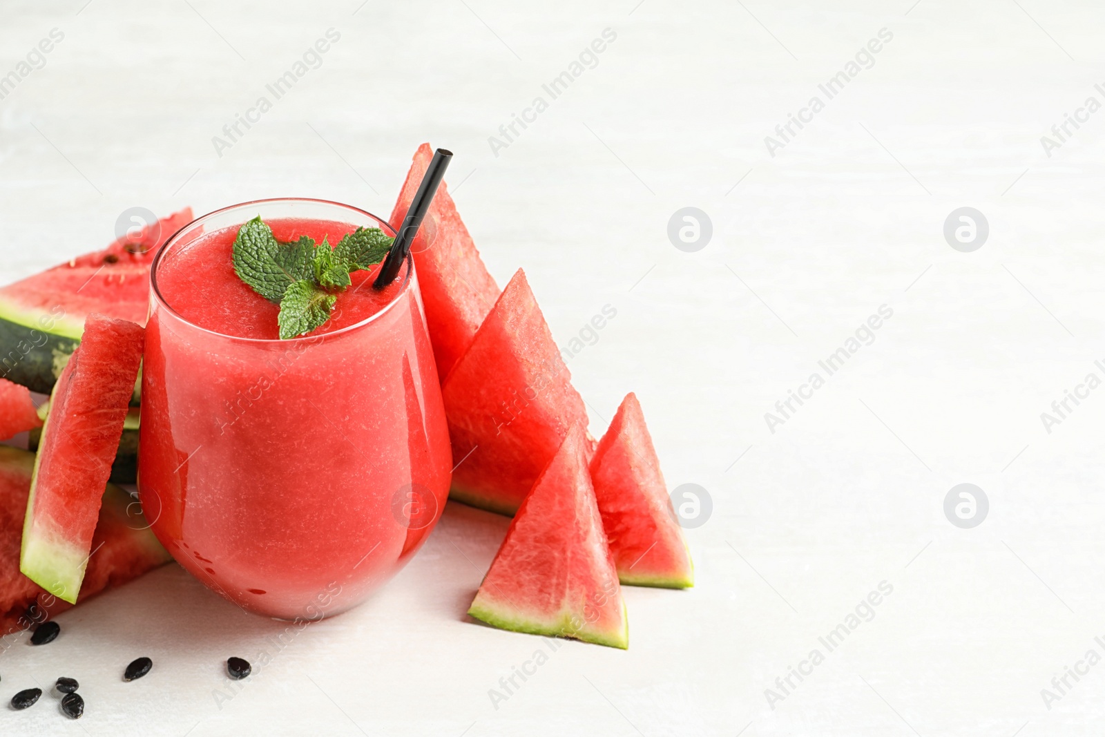 Photo of Summer watermelon drink in glass, sliced fresh fruit and space for text on table