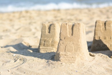 Photo of Beautiful sand castles on beach near sea, space for text