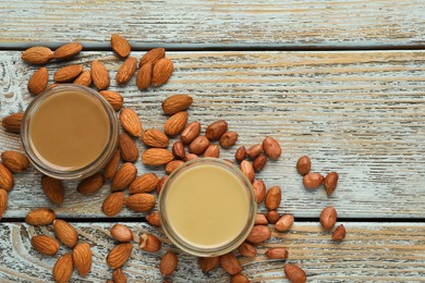 Photo of Different types of delicious nut butters and ingredients on light blue wooden table, flat lay. Space for text