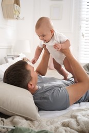 Photo of Father with his cute baby on bed at home. Happy family