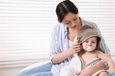 Mother wrapping her cute little baby with towel after bathing on bed, space for text