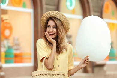 Happy young woman with cotton candy outdoors