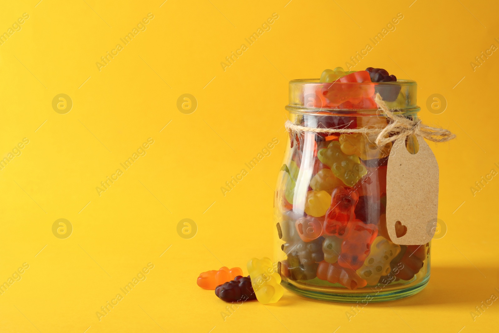 Photo of Delicious gummy bear candies on yellow background. Space for text