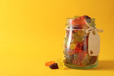 Photo of Delicious gummy bear candies on yellow background. Space for text